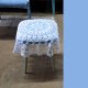 Taboret stołek z siedziskiem w kolorze błękitnym i białą ażurową narzutką.