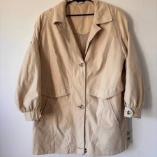 Klasyczny beżowy trencz w minimalistycznym stylu, zapinany na duże guziki.