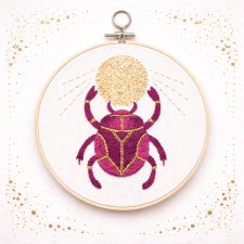 Skarabeusz w tamborku, talizman odrodzenia i twórczości.