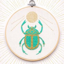 Skarabeusz w tamborku, talizman odrodzenia i twórczości.